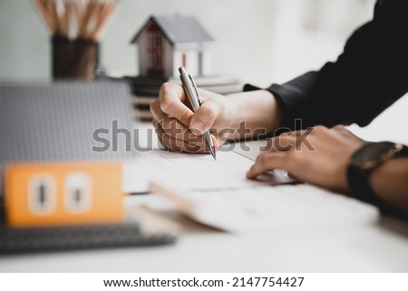 Real estate salespeople are reviewing the real estate sales contract documents before the customer agrees to sign the contract to buy the housing in the project. Real estate trading concept.
