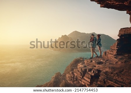 What a great photo opportunity. Full length shot of a young man taking picture of the view while hiking with his girlfriend.