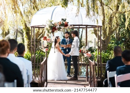 Stepping into holy matrimony. Cropped shot of a handsome young male marriage officiant joining a young couple in marriage outdoors. Royalty-Free Stock Photo #2147754477