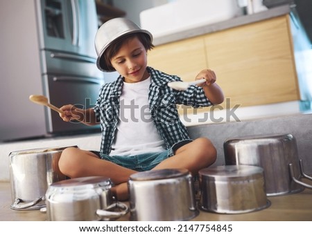Unleashing an epic drum solo. Shot of a happy little boy playing drums with pots on the kitchen floor while wearing a bowl on his head. Royalty-Free Stock Photo #2147754845