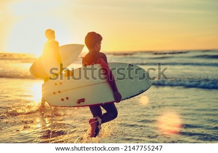 Keep calm and surf on. Shot of two young brothers carrying their surfboards while wading into the ocean. Royalty-Free Stock Photo #2147755247