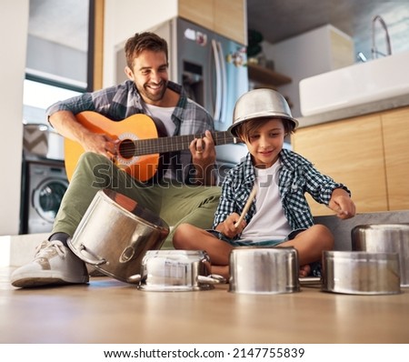 Its a father-son collaboration. Shot of a happy father accompanying his young son on the guitar while he drums on a set of cooking pots. Royalty-Free Stock Photo #2147755839