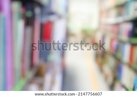 Blurred of interior of the public library with books in wooden bookshelves. Education and book's day background concept.
