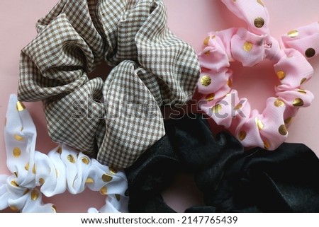 Various cute scrunchies on pastel pink background. Flat lay.
