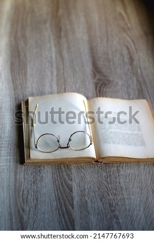 Open book and reading glasses on the table. Selective focus.