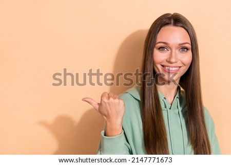 Portrait of attractive cheerful girl demonstrating copy blank space ad solution isolated over beige pastel color background