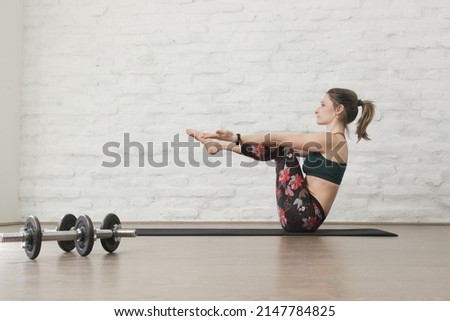 Young woman practicing strength yoga positions. Wellbeing and self care concept. Yoga poses for absand core strength, serie of photos.