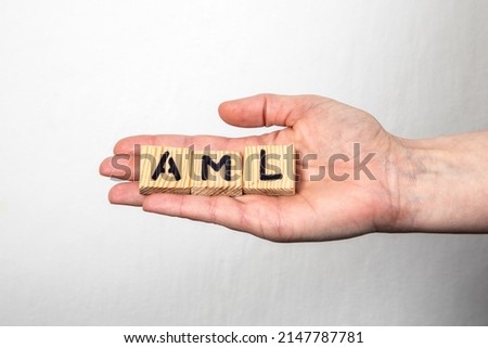 AML Anti Money Laundering. Wooden alphabet letters in a woman's hand.