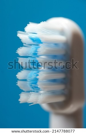 Electric ultrasonic toothbrush bristles on blue background.