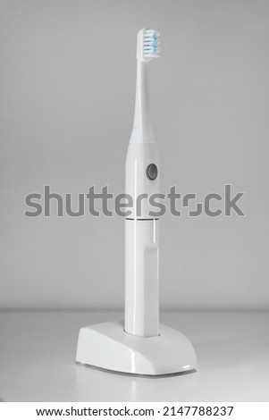 Electric ultrasonic toothbrush on grey background.