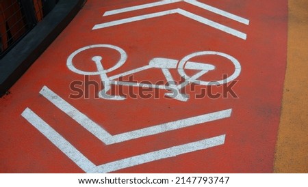 Orange bicycle path with white bicycle symbol