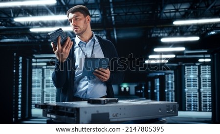 Successful Data Center IT Specialist Using Tablet Computer. Server Farm Cloud Computing Facility with System Administrator Working. Data Protection Engineering Network for Cyber Security.