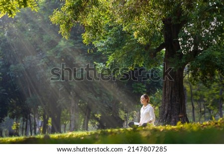Woman relaxingly practicing meditation in the forest to attain happiness from inner peace wisdom with beam of sun light for healthy mind and soul Royalty-Free Stock Photo #2147807285