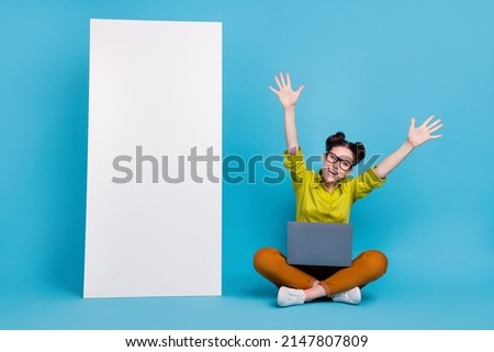Full length photo of positive lady sit floor raise hands large phone banner isolated on blue color background