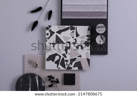 Creative flat lay composition in grey and black color palette with textile and paint samples, panels and lastrico tile. Architect and interior designer moodboard. Top view. Copy space. Template.
