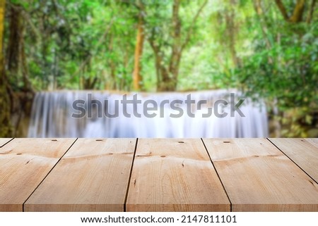 Close-up empty wooden plank long table top on vintage style for put product and anything display with outdoor theme on blurred waterfall background