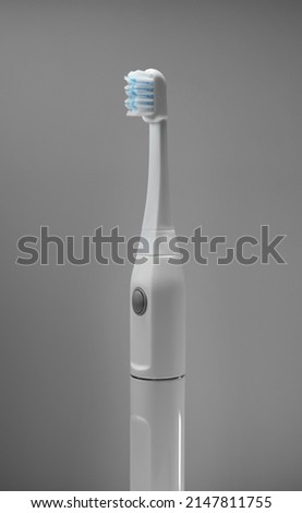 Electric ultrasonic toothbrush on grey background.