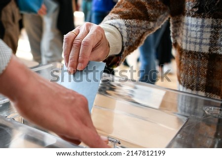 A ballot paper in its envelope, held in the hand by a lady, just before being placed in the ballot box Royalty-Free Stock Photo #2147812199