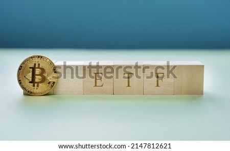bitcoin icon standing with wooden cubes with "ETF" text. Exchange Traded Fund (ETF) and bitcoin cryptocurrency concept. the digital money fund concept. blue background. 