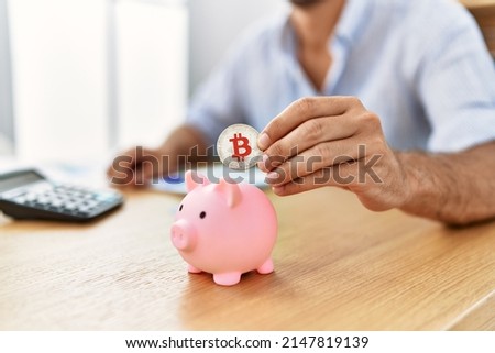 Businessman insert bitcoin in piggy bank at the office.