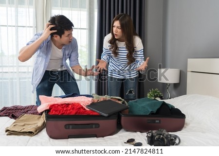 stressed couple having problem with packing clothes into a suitcase on a bed at home, holiday travel concept Royalty-Free Stock Photo #2147824811