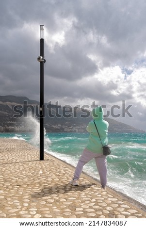 Young girl takes pictures of a beautiful, stormy ocean.