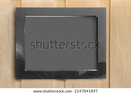 Empty black frame hanging on wooden wall