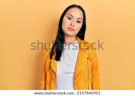 Beautiful hispanic woman with nose piercing wearing yellow leather jacket looking sleepy and tired, exhausted for fatigue and hangover, lazy eyes in the morning. 