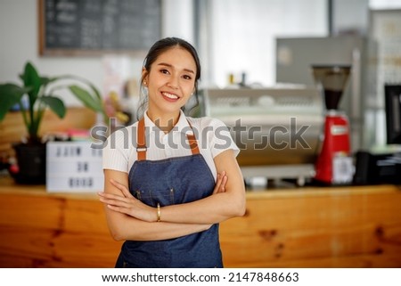 Opening a small business, AHappy Asian woman in an apron standing  near a bar counter coffee shop, Small business owner, restaurant, barista, cafe, Online, SME, entrepreneur, and  seller concept Royalty-Free Stock Photo #2147848663