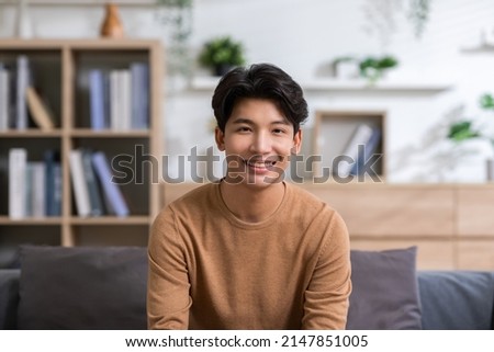 Asian handsome man looking at camera smile at home.Happy young smart businessman smile and confidence.Positive and good moment of asian male worker smile  with wellness life Royalty-Free Stock Photo #2147851005