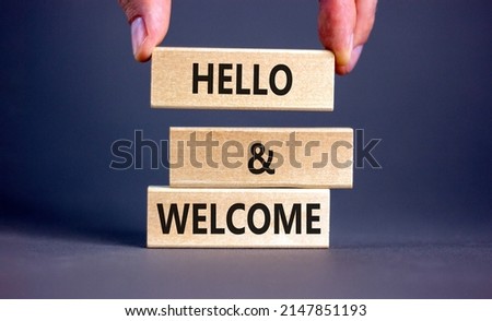 Hello and welcome symbol. Concept words Hello and welcome on wooden blocks. Businessman hand. Beautiful grey table grey background. Business hello and welcome concept. Copy space.