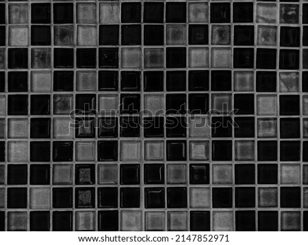 A square grid of tiled walls in black and white tones as a background.