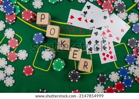The word poker on wooden cubes, poker chips with playing cards on the green casino table. gamble