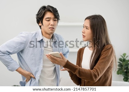 Infidelity, suspicion Asian young couple love fight relationship, wife holding a cellphone. distrust and jealousy when sitting at home. Royalty-Free Stock Photo #2147857701
