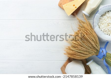Shavuot jewish holiday celebration. Milk and cheese, ripe wheat and fruits, cream on white wooden background. Dairy products over white wooden background. Shavuot concept. Top view. Mock up. Royalty-Free Stock Photo #2147858139