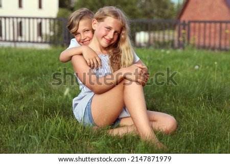 Caucasian brother with sister in the park on the grass. High quality photo