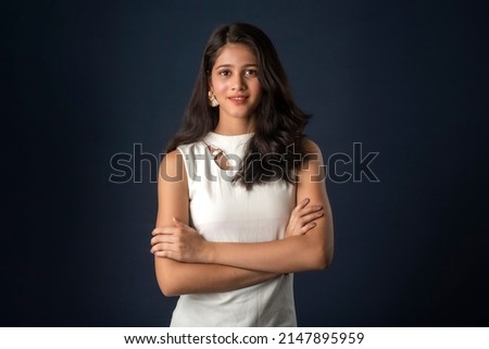 Portrait of a beautiful, smiling, emotional young woman posing with hands-folded on gray background. Royalty-Free Stock Photo #2147895959