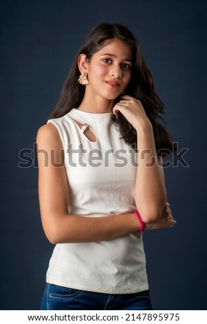 Portrait of a beautiful, smiling, emotional young woman posing with hands-folded on gray background.