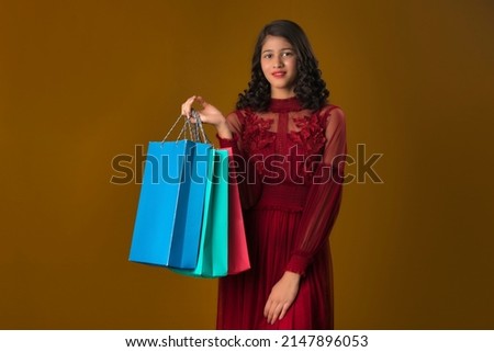 Beautiful Indian young girl holding and posing with shopping bags on a brown background