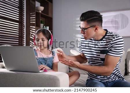 Internet addiction. Man scolding his daughter while she using laptop in living room