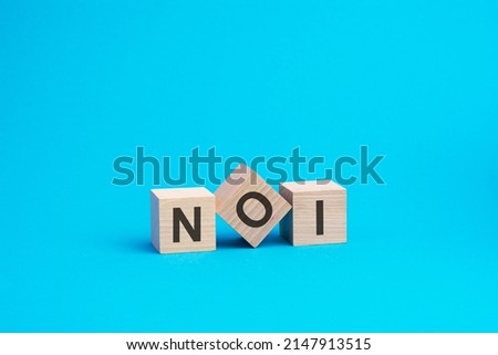 noi text on wooden blocks, financial business concept, blue background. noi - short for net operating income