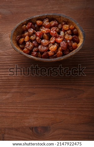 Raisins in a bowl of coconut shell on a wooden table.copy space Vertical photo