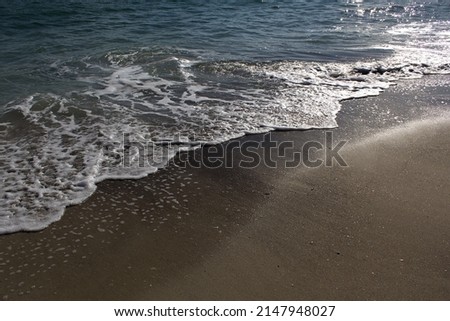 Sea water waves on sandy summer beach into sun light 