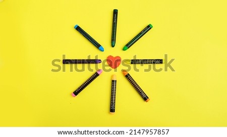 Pencils with LGBT colors, lgbt colored pencils pointing to the heart close up on yellow background, lgbt pencil and heart top view