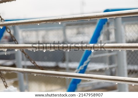 handrail, railing with water drops and wet snow build-up. early spring weather conditions, thaw and snow melting Royalty-Free Stock Photo #2147958907