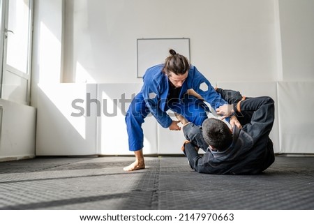 Two brazilian jiu jitsu BJJ athletes training at the academy martial arts ground fighting sparring wear kimono gi sport uniform on the tatami mats sports jiujitsu and self-defense concept copy space Royalty-Free Stock Photo #2147970663