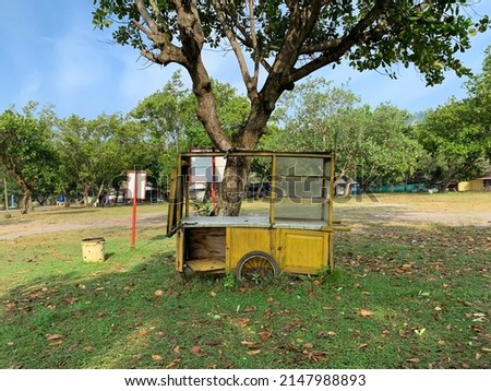 Abandoned wood food cart with yellow color under the tree