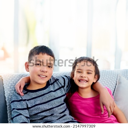 Were closer than you think. Portrait of two adorable young siblings posing with their arms around each other while relaxing on a sofa at home.