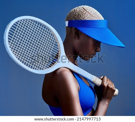 I have what it takes to be great. Studio shot of a sporty young woman posing with a tennis racket against a blue background.
