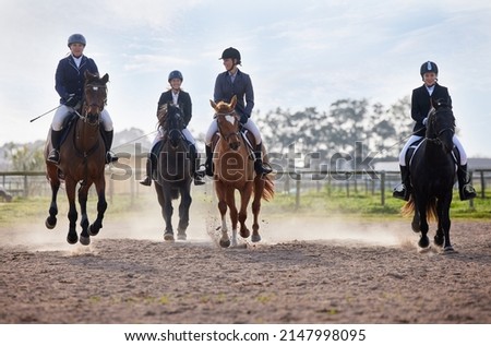 Theyre neck-and-neck. Full length shot of a group of attractive young female jockeys riding their horses out on the farm.